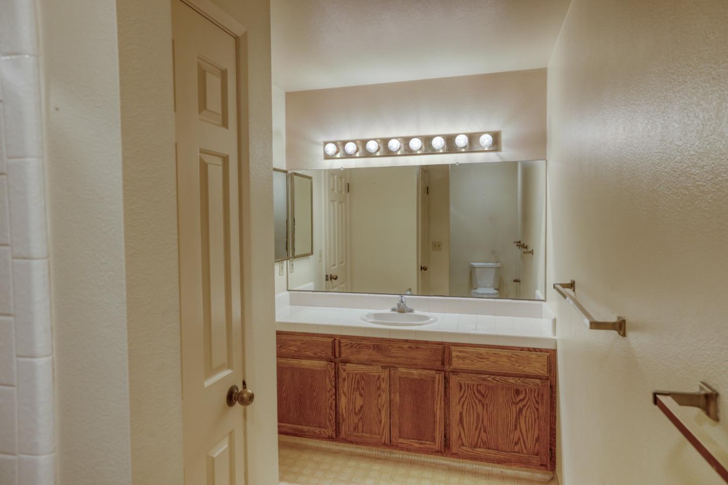 Bathroom with a large mirror, white countertop, and long wood vanity.