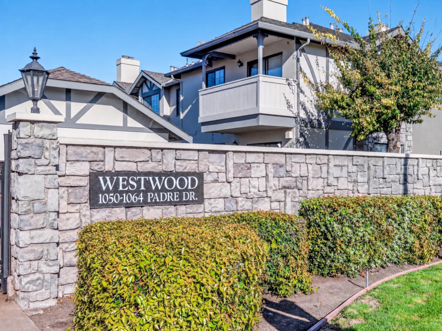 Westwood residential property behind a stone sign wall and landscaped hedges.