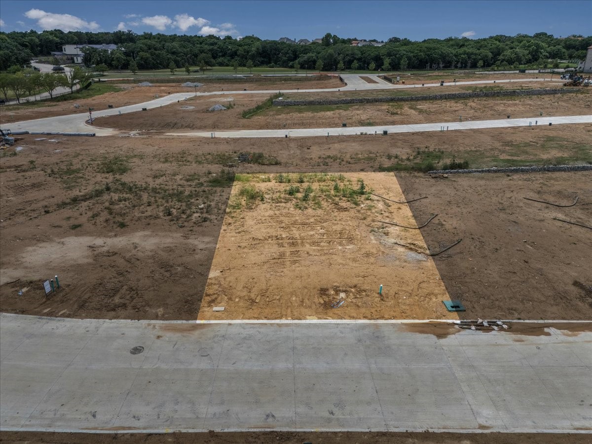 Highlighted vacant residential lot amid graded land and newly paved subdivision streets.