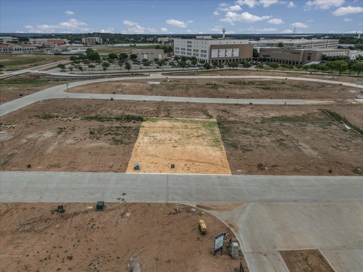 Highlighted vacant lot amid new streets, with commercial buildings in the distance.