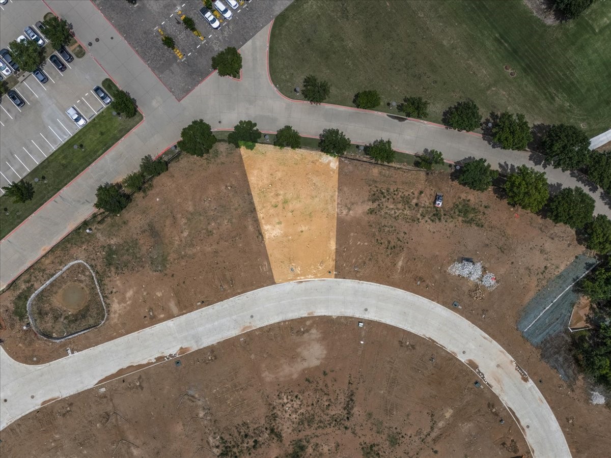 Aerial view of a vacant lot highlighted beside a curved street.