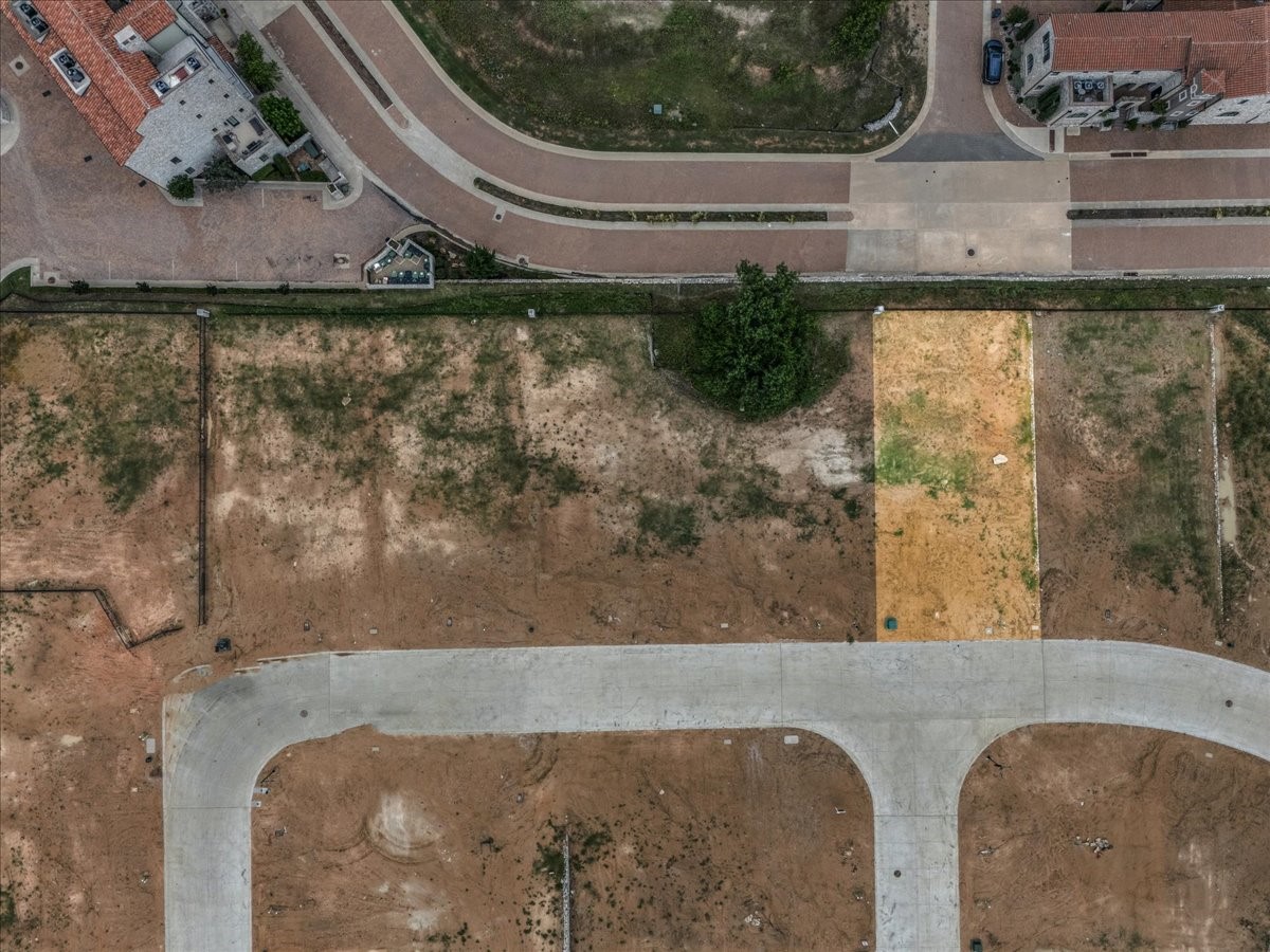 Aerial view of vacant residential lots beside new streets and finished homes.