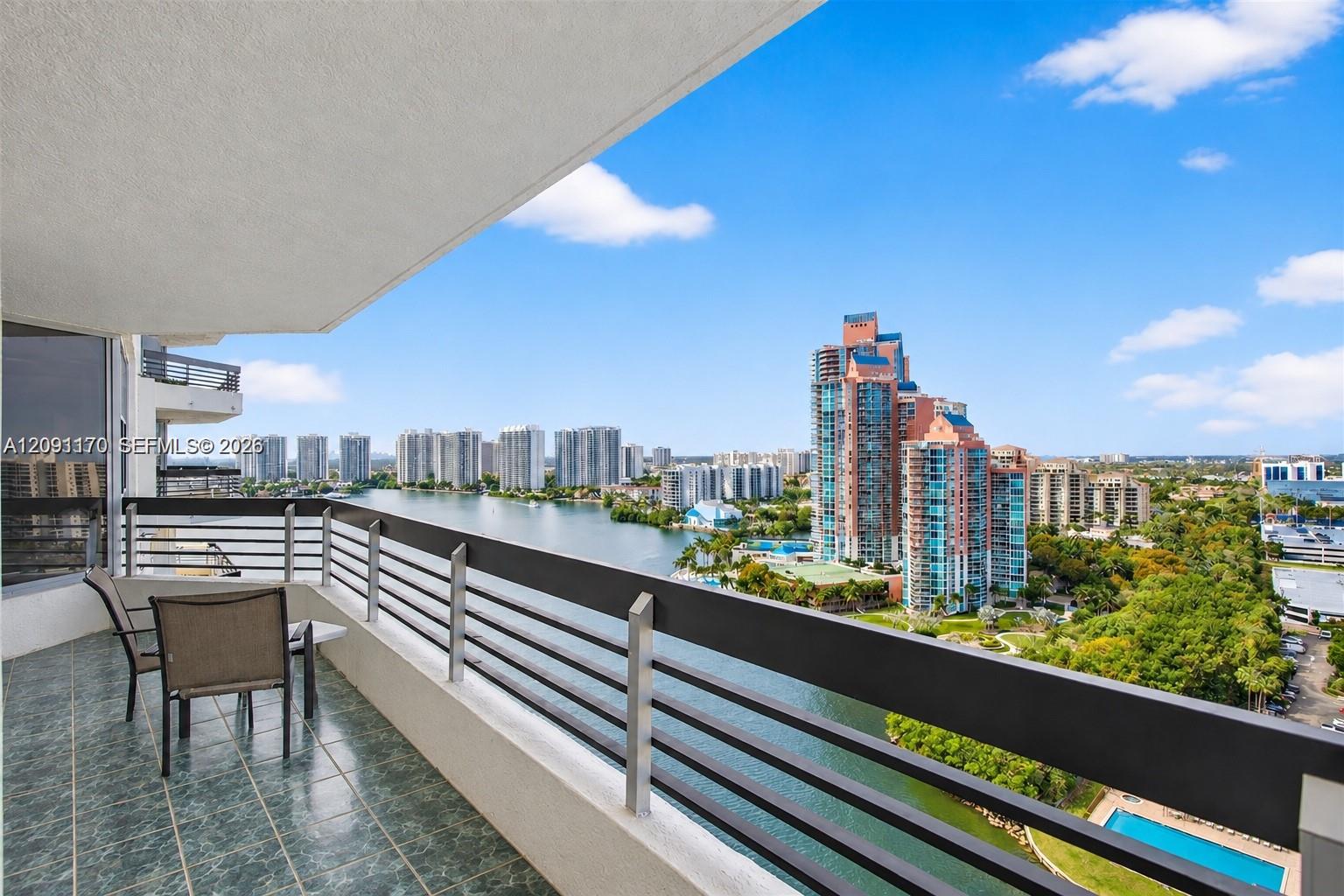 High-rise balcony overlooking the water and Aventura skyline, with an outdoor table and chairs.