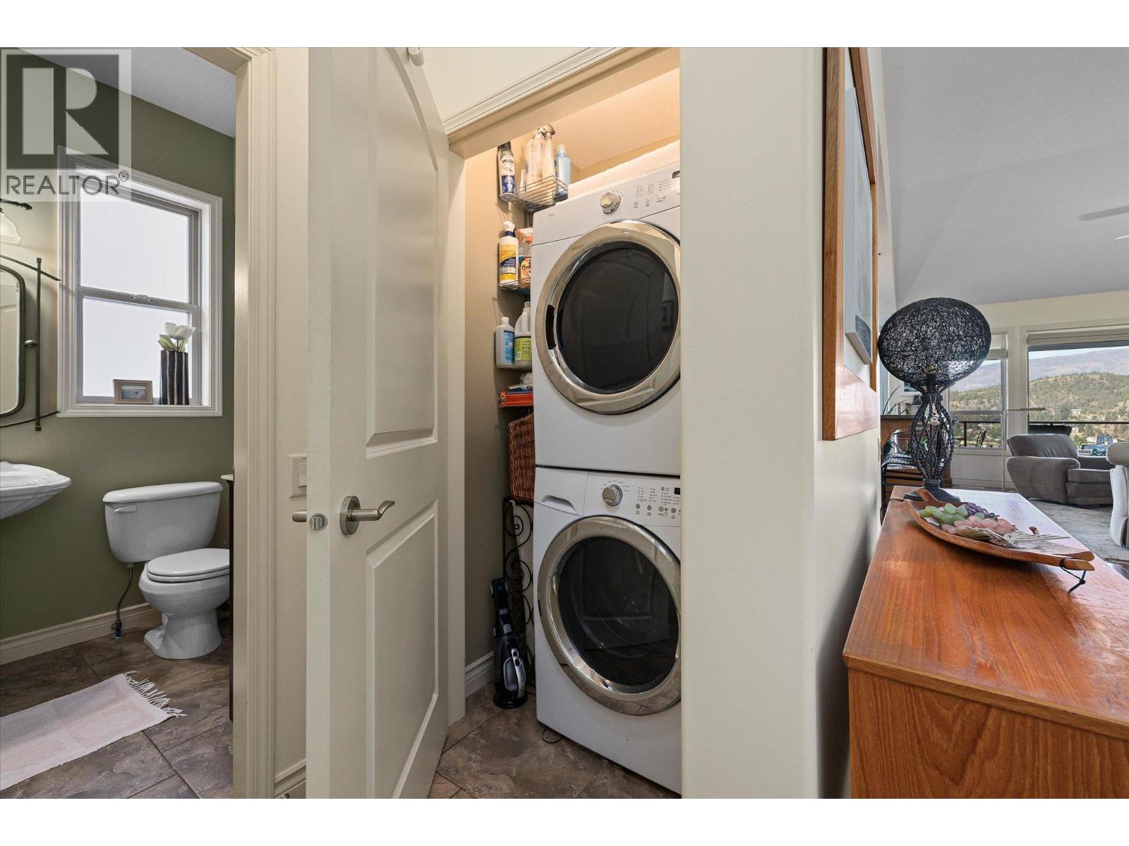 Stacked washer and dryer beside a powder room, with a mountain view visible through the living room windows.