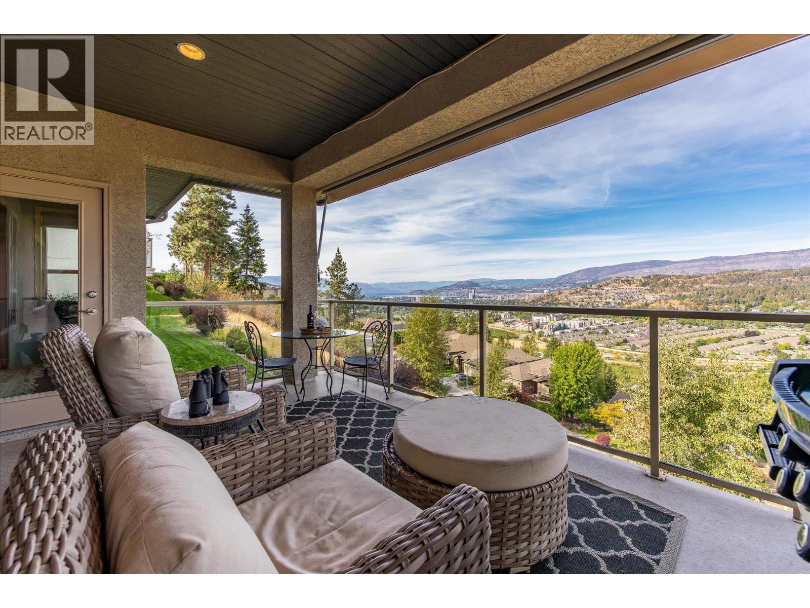 Covered balcony with wicker seating and panoramic views of the city and surrounding hills.