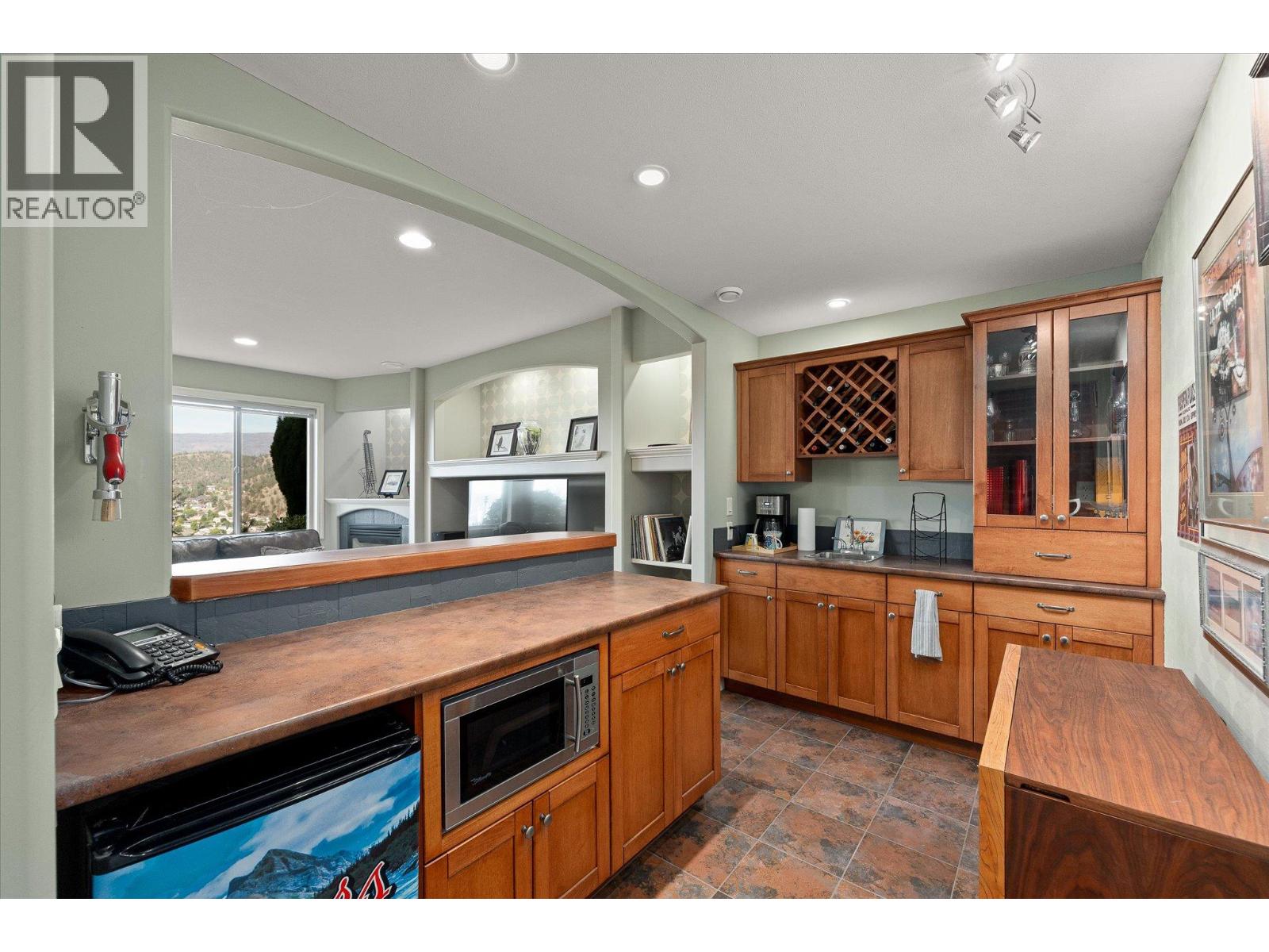Kitchen and bar with warm wood cabinetry, built-in wine rack, and open view to the living room.