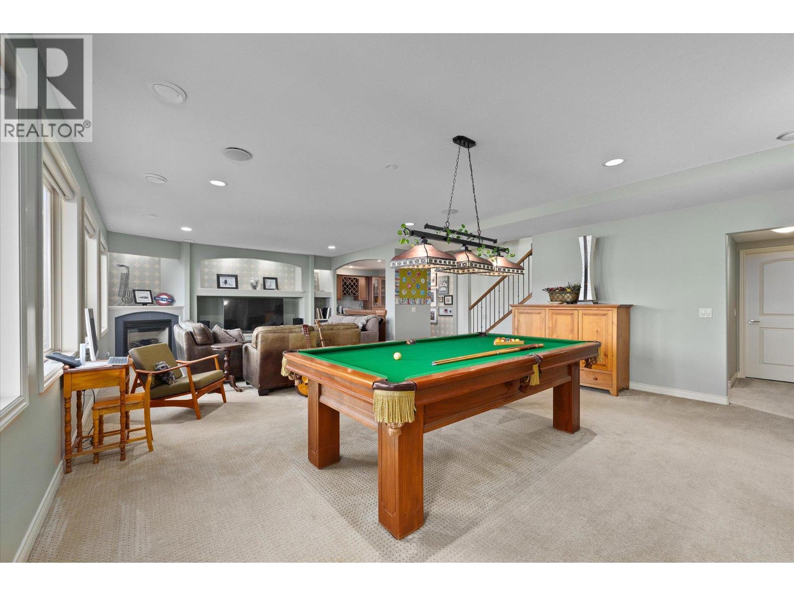 Recreation room with a green-felt pool table, fireplace, and seating area.
