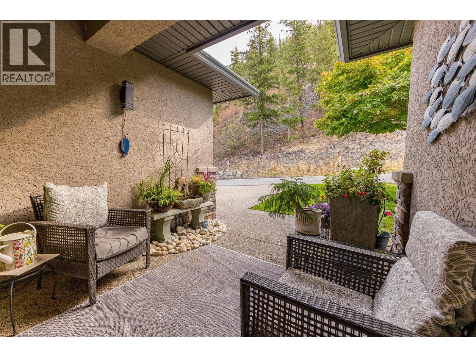 Covered patio with wicker seating and potted plants overlooking an autumn hillside.