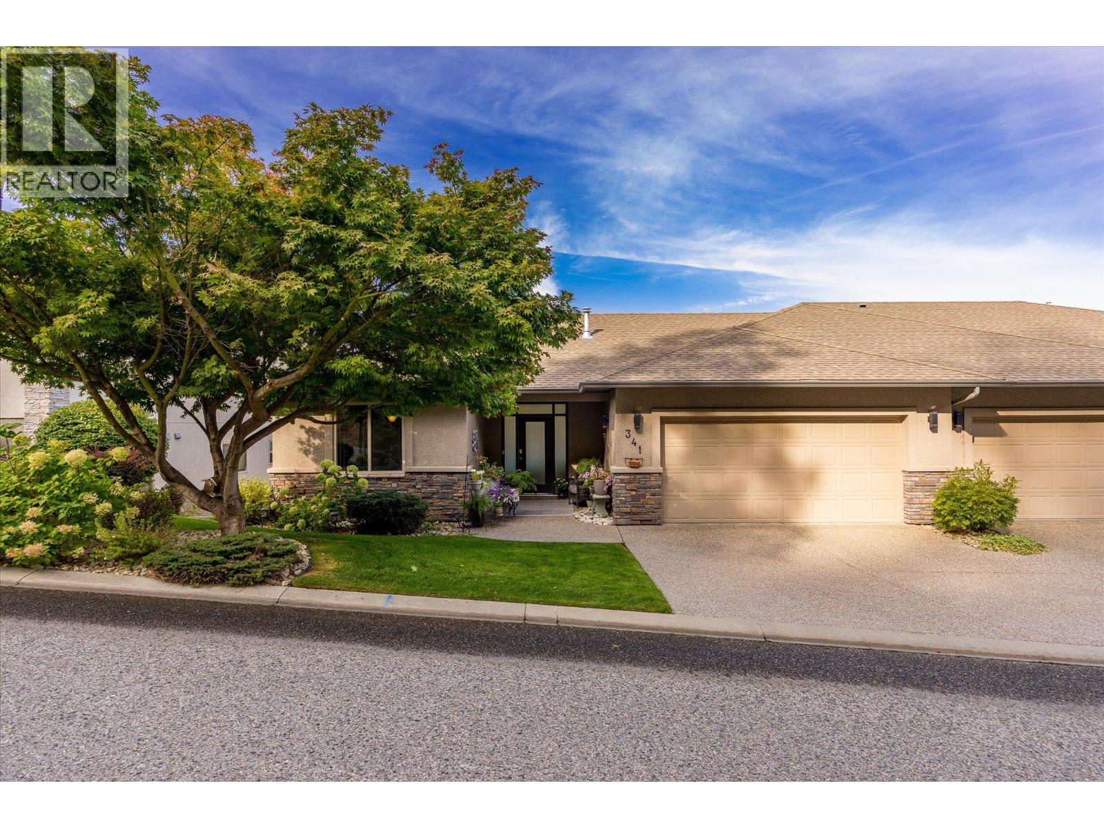 Attached home with double garage, stone accents, and a leafy tree in the front garden.