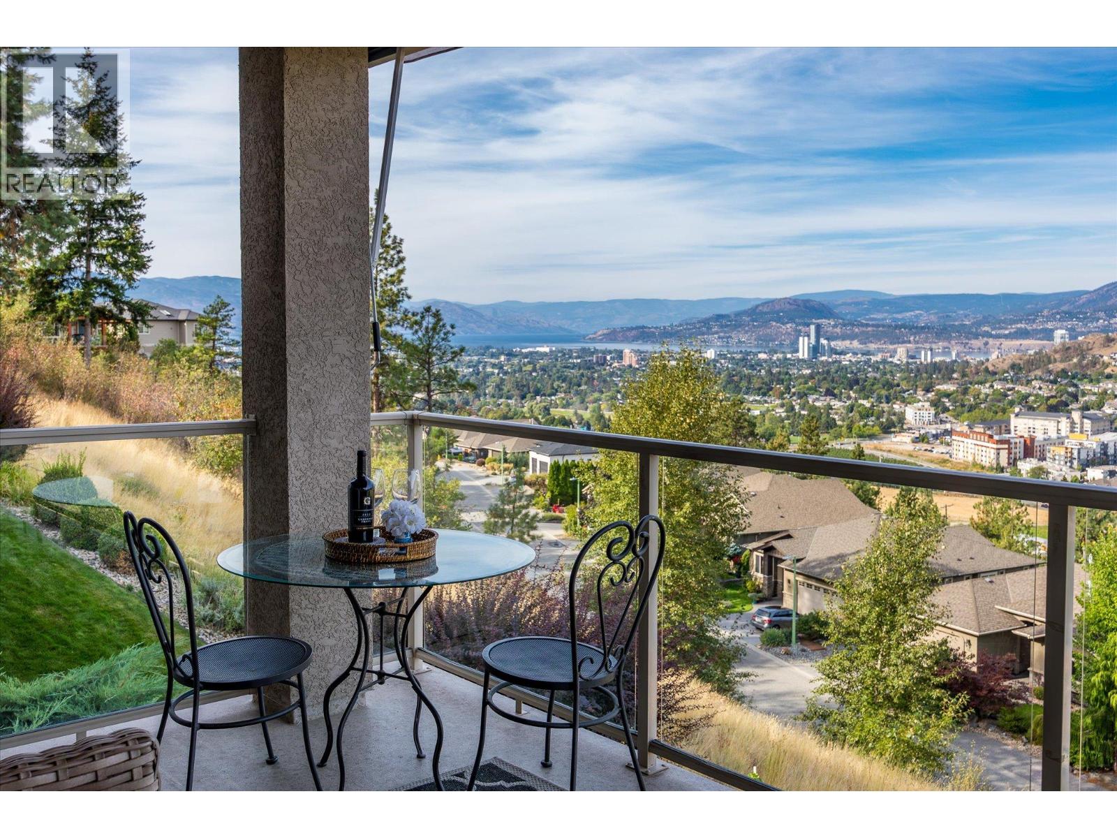 Balcony with outdoor seating overlooking Kelowna, Okanagan Lake, and distant mountains