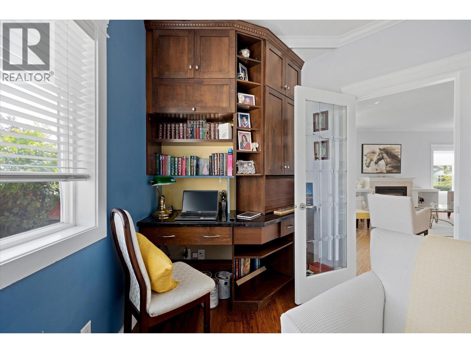 Home office with dark wood built-ins, a desk and laptop, and an open door to the living room.