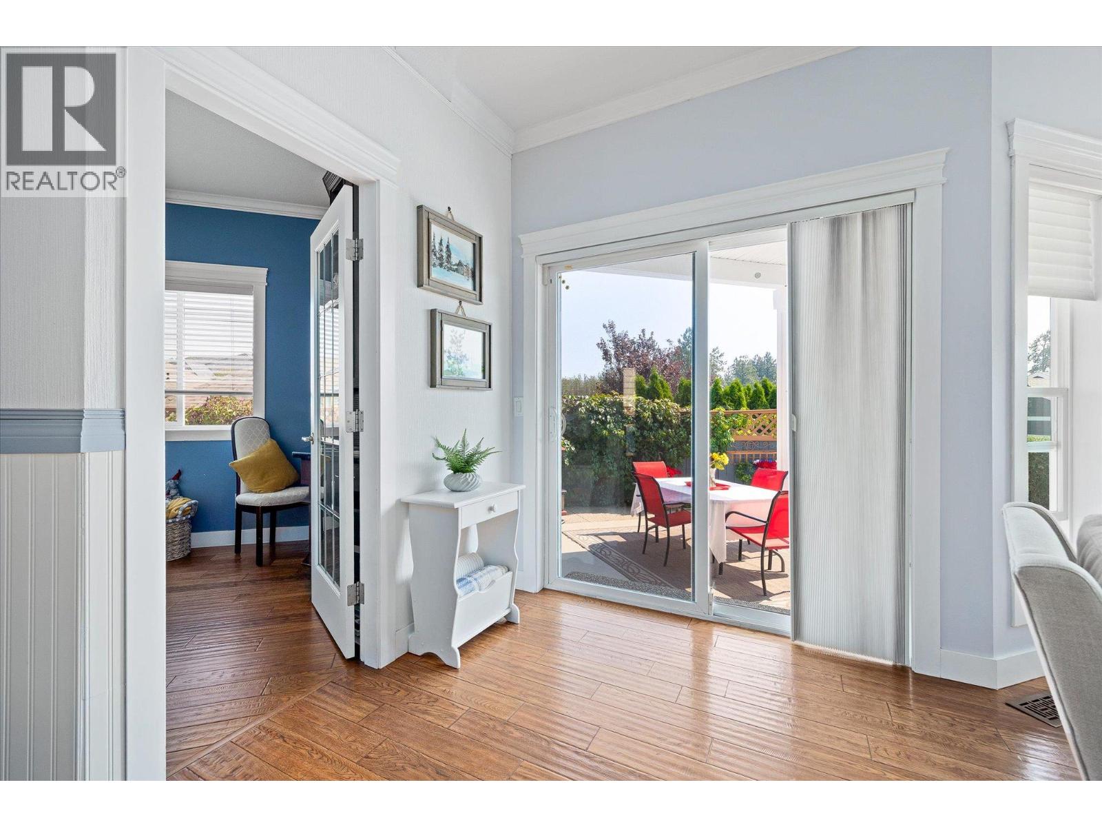 Bright living area with wood flooring and sliding doors opening to a furnished patio.