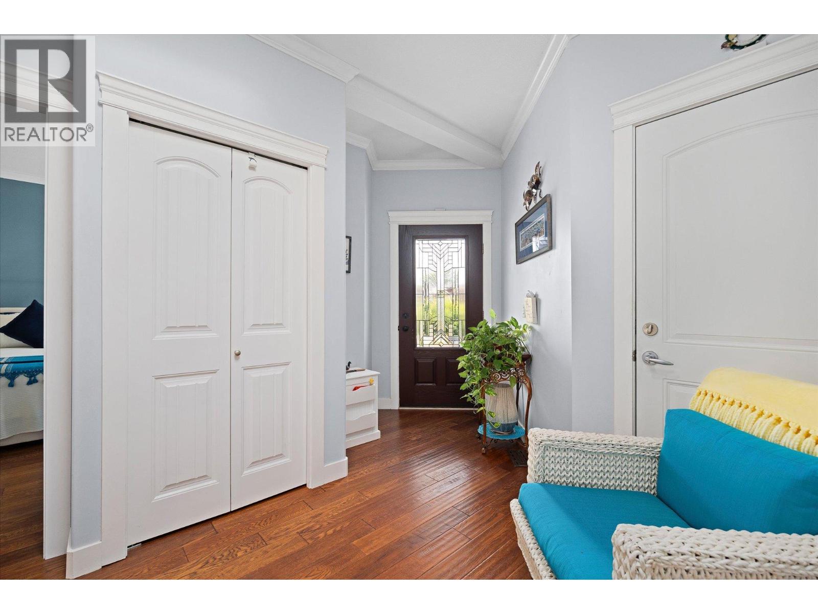 Entryway with a decorative-glass front door, white closet doors, hardwood floors, and turquoise seating.
