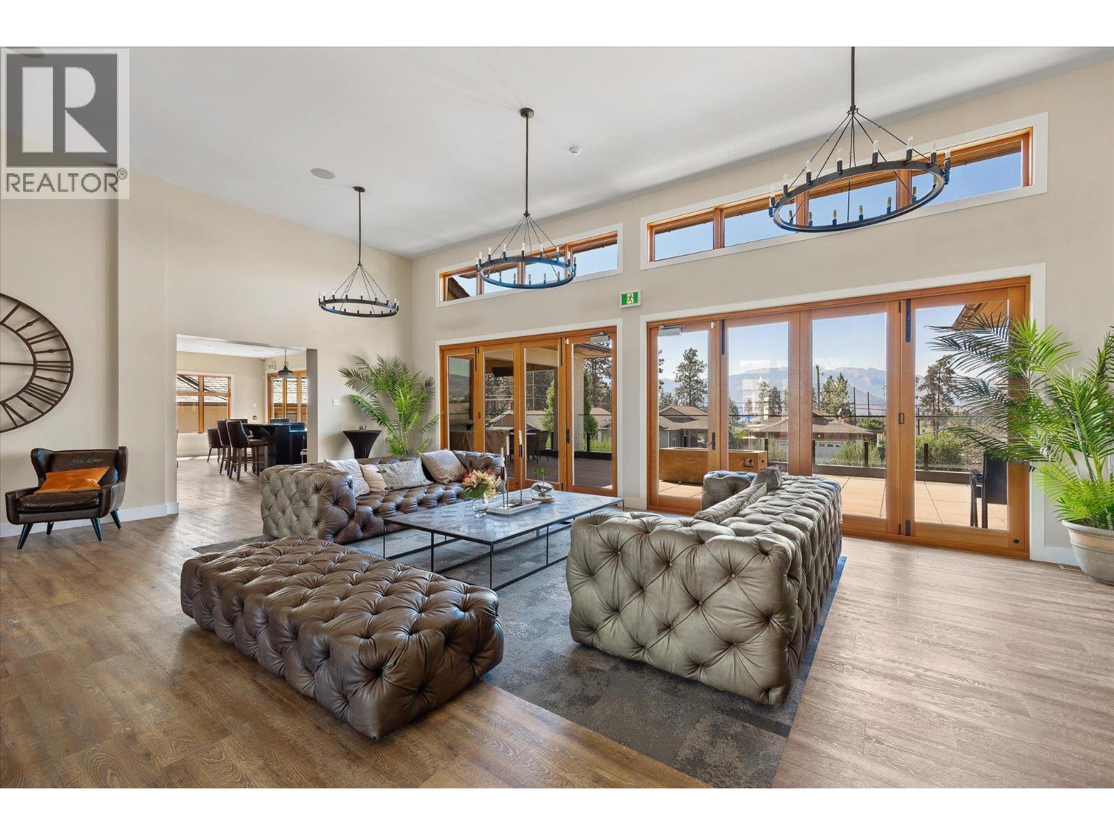 Living room with tufted leather seating, high ceilings, and expansive glass doors overlooking a deck and mountains.