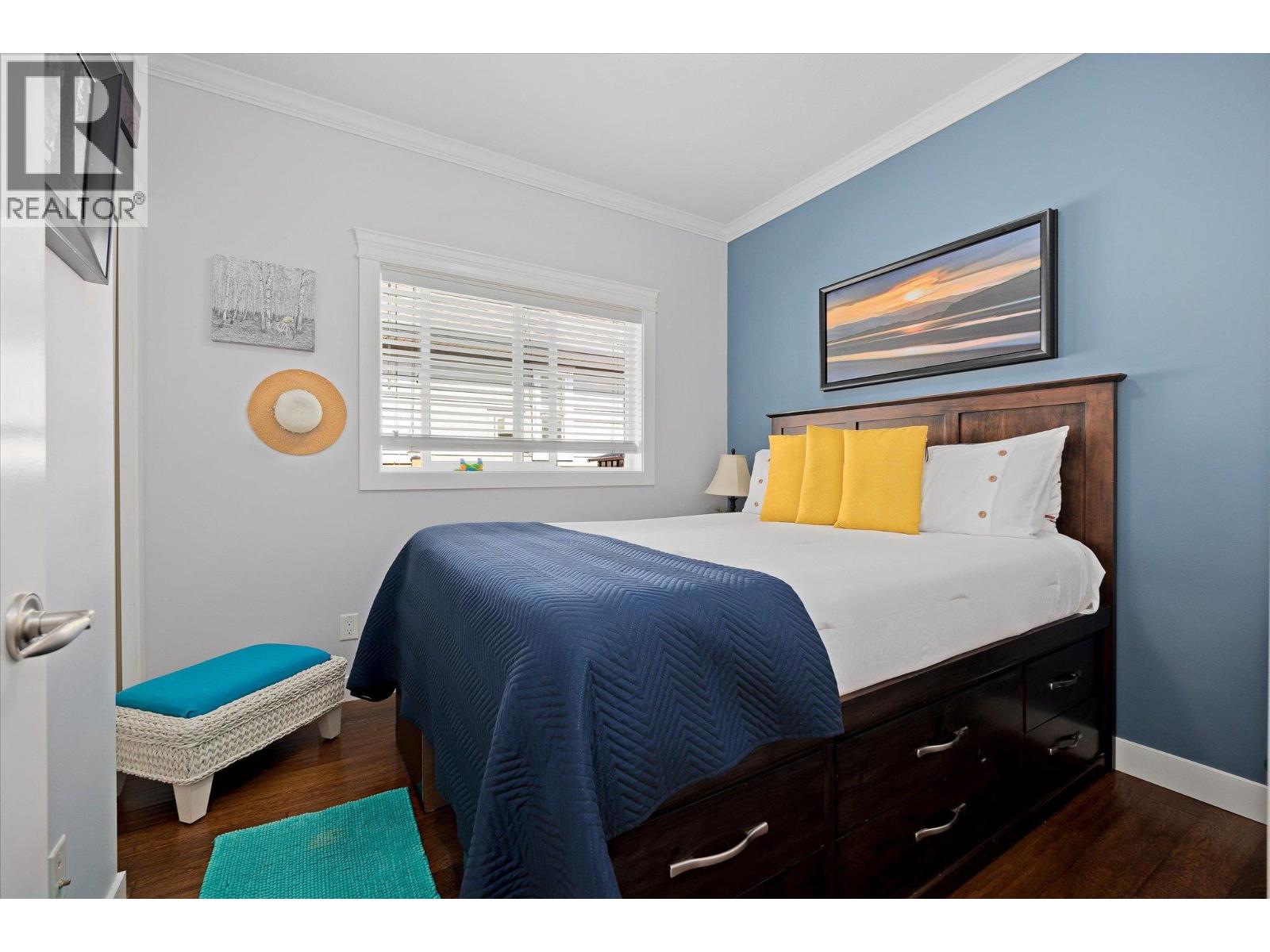 Furnished bedroom with a dark wood storage bed, navy quilt, yellow pillows, and blue accent wall.