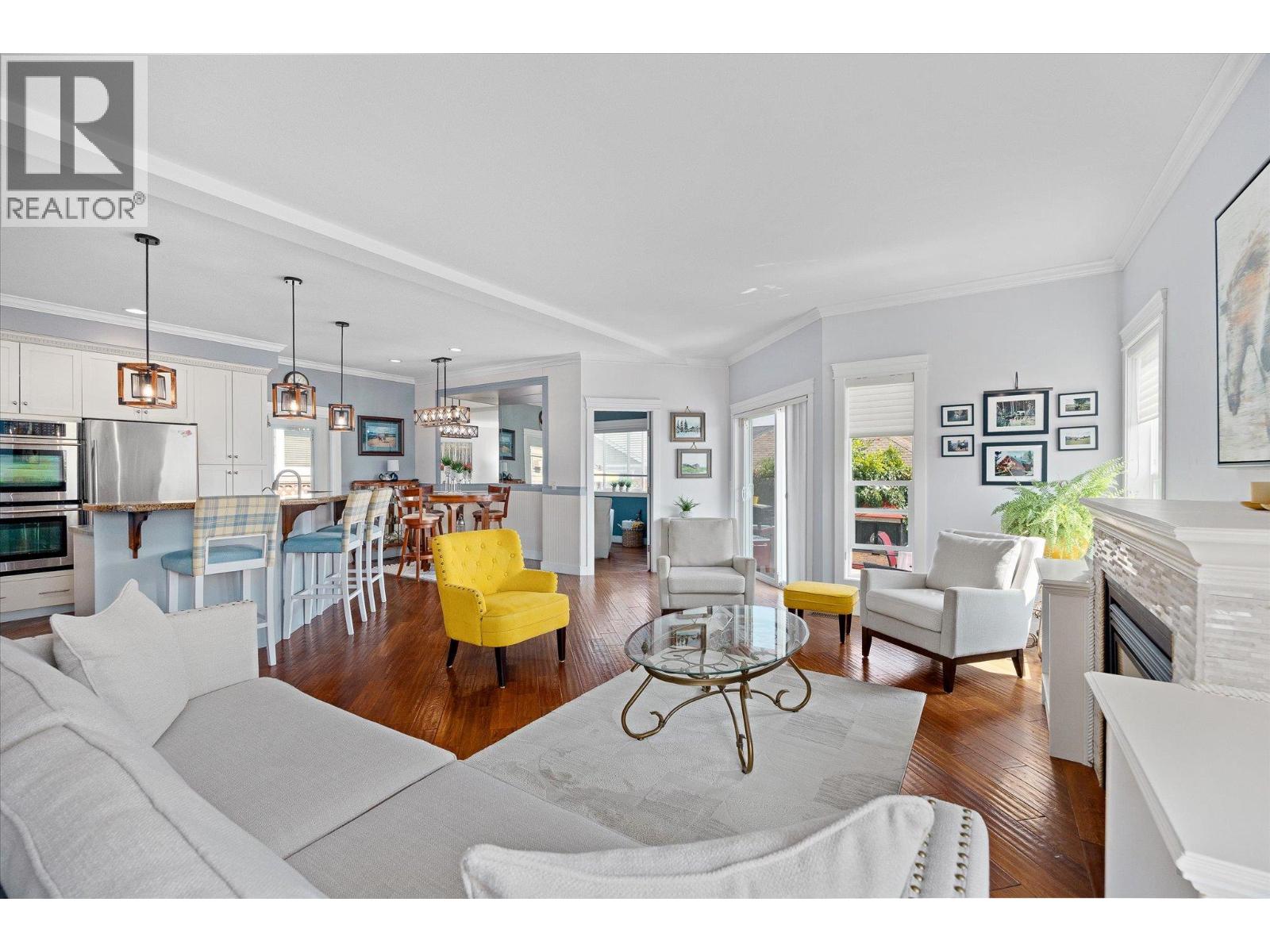 Open-plan living room and kitchen with hardwood floors, a fireplace, and a yellow accent chair.