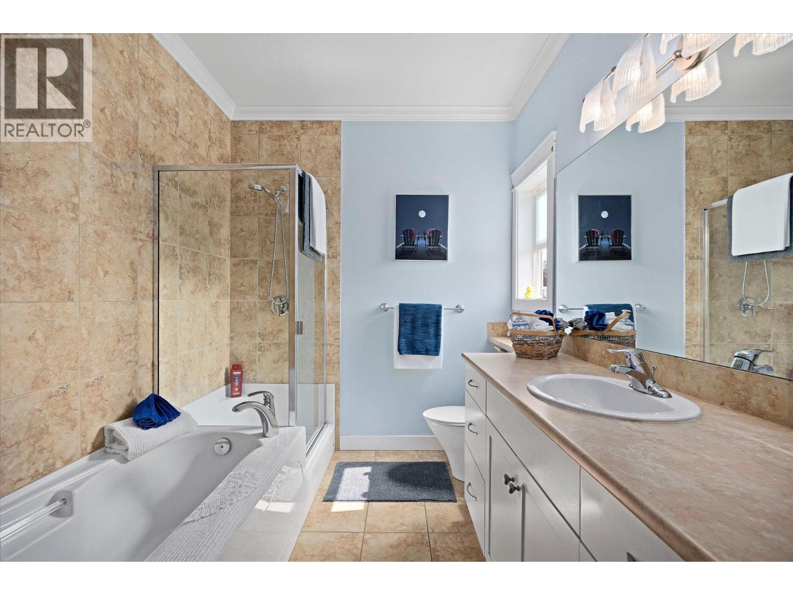 Bathroom with a glass-enclosed shower, bathtub, and long vanity beneath a large mirror.