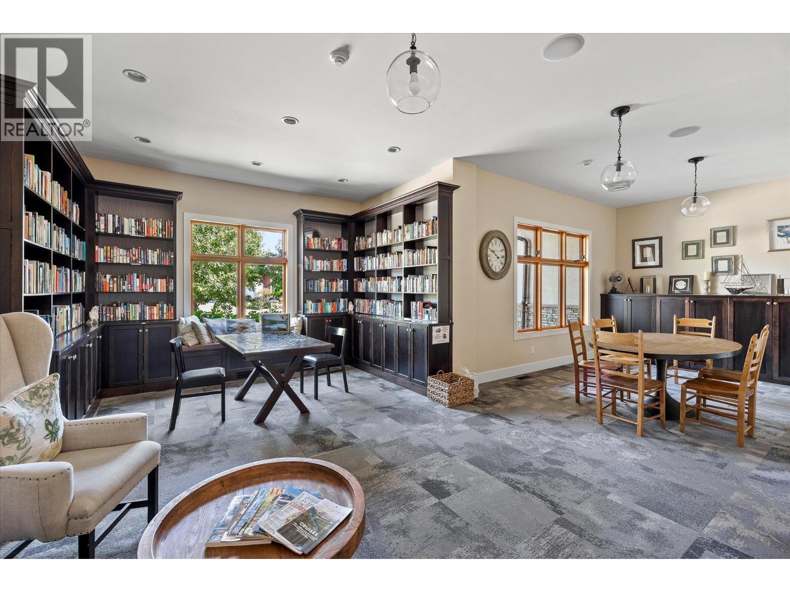 Home library with dark built-in bookshelves, reading table, and adjoining dining area.