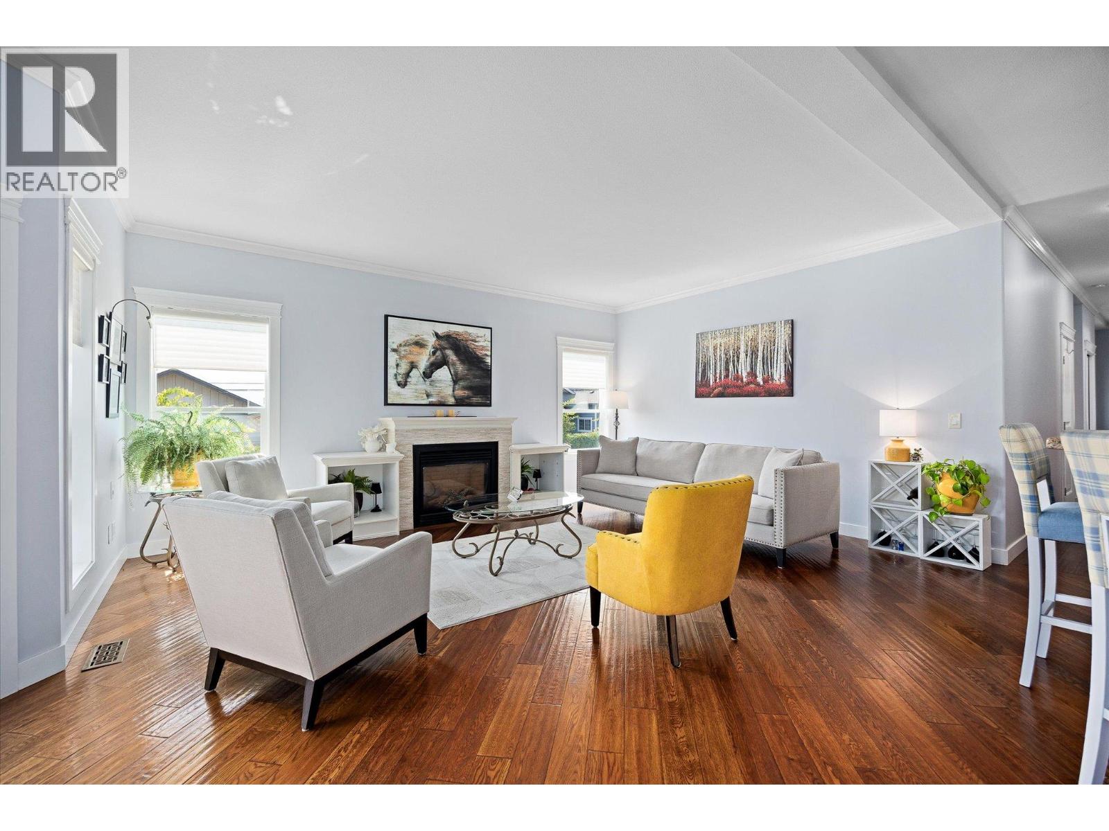 Living room with a fireplace, dark hardwood floors, gray seating, and a yellow accent chair.