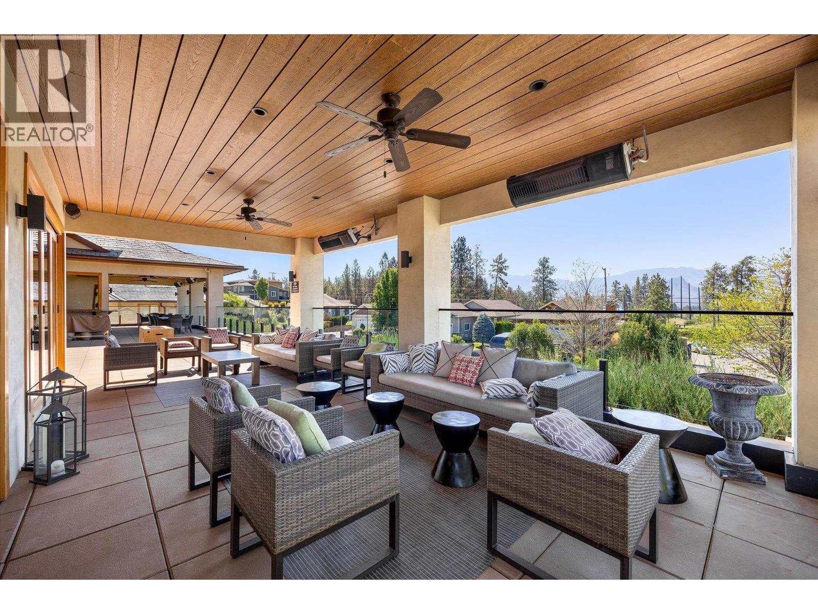 Covered patio with wicker lounge seating, a wood ceiling, ceiling fans, and distant mountain views.