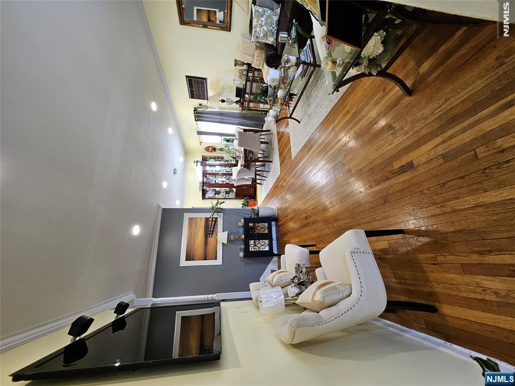 Open-plan living and dining room with polished hardwood floors and cream seating.