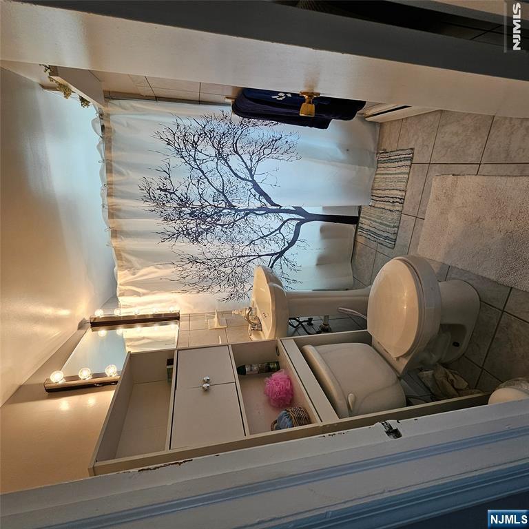 Bathroom with built-in shelving and a tree-print shower curtain.