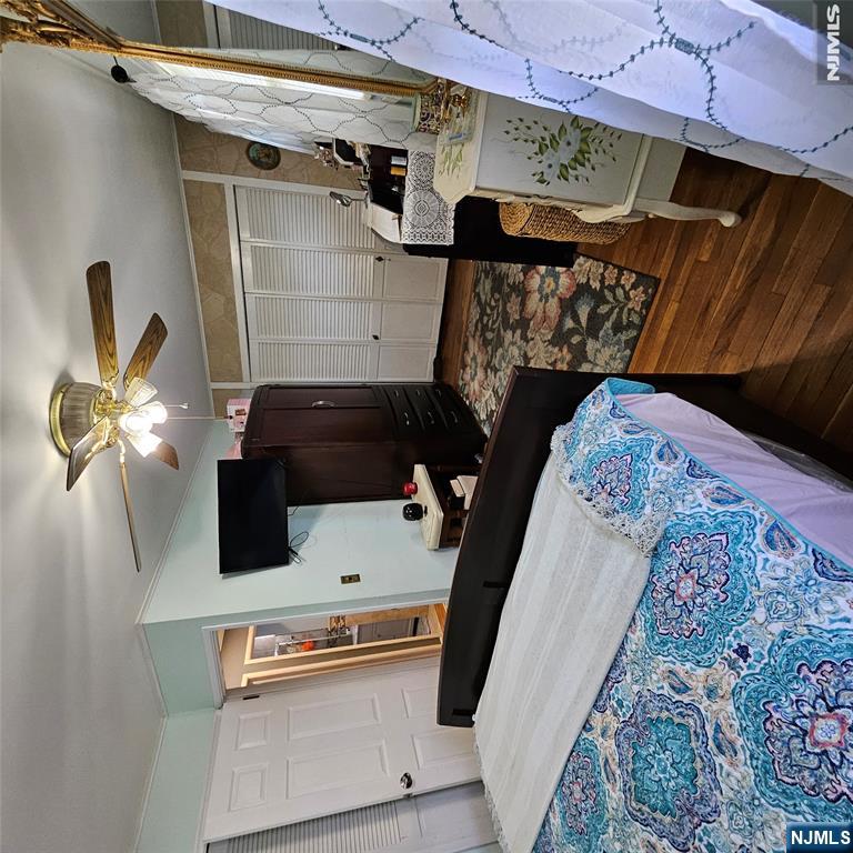 Furnished bedroom with a blue patterned bedspread, dark wood furniture, and white louvered closet doors.