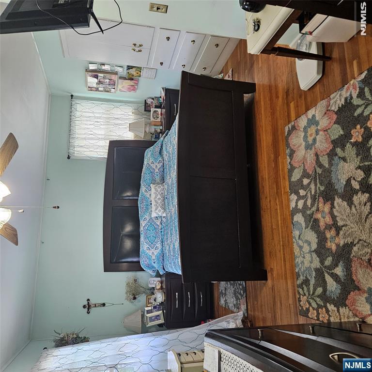 Furnished bedroom with a dark wood bed, blue patterned bedding, hardwood floors, and floral rugs.