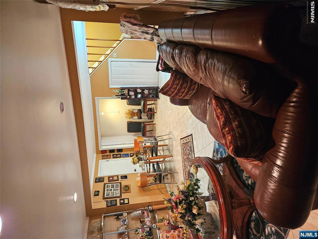 Living room with a brown leather sectional, glass coffee table, and dining area beside the staircase.