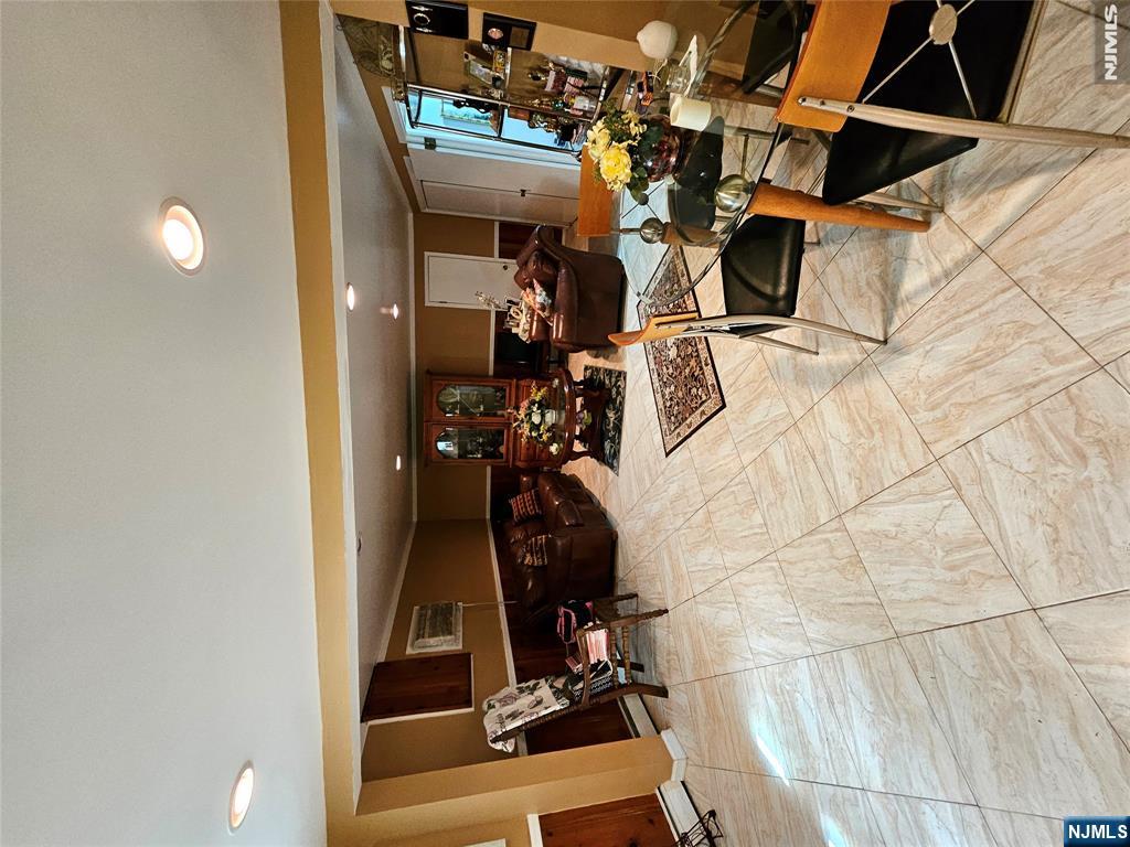 Living and dining room with cream tile floors, brown leather seating, and a glass dining table.
