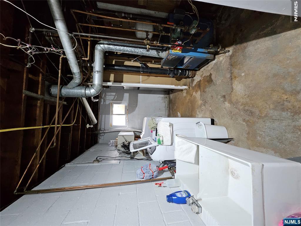 Unfinished basement laundry area with a deep wash sink, washing machine, and exposed ductwork.