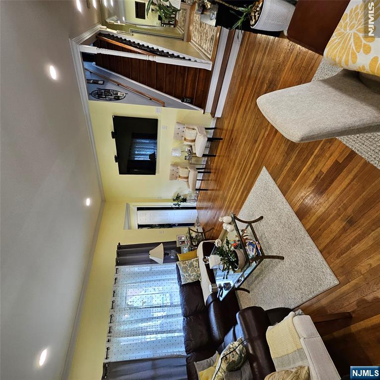 Furnished living room with hardwood floors, yellow walls, and a prominent staircase.