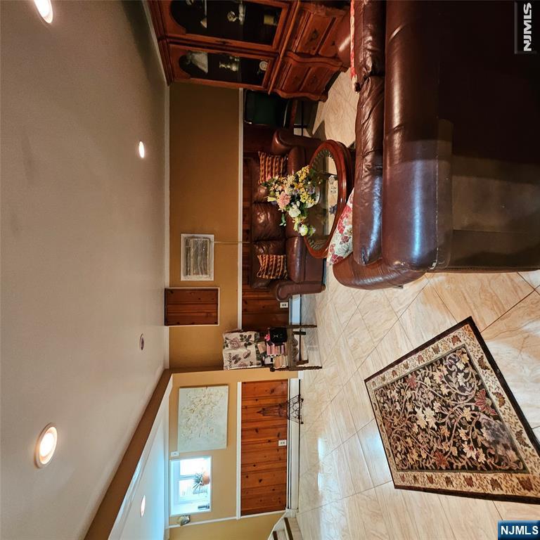 Living room with brown leather sofas, a flower-topped coffee table, and a wooden display cabinet.