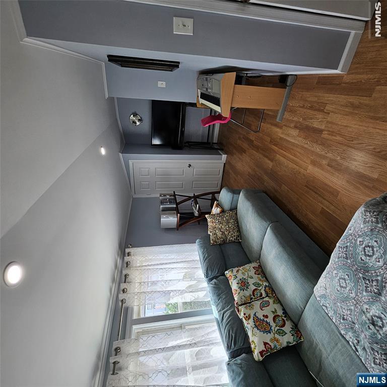 Furnished living room with a teal sectional, curtained windows, wood-look floors, and an electronic keyboard.