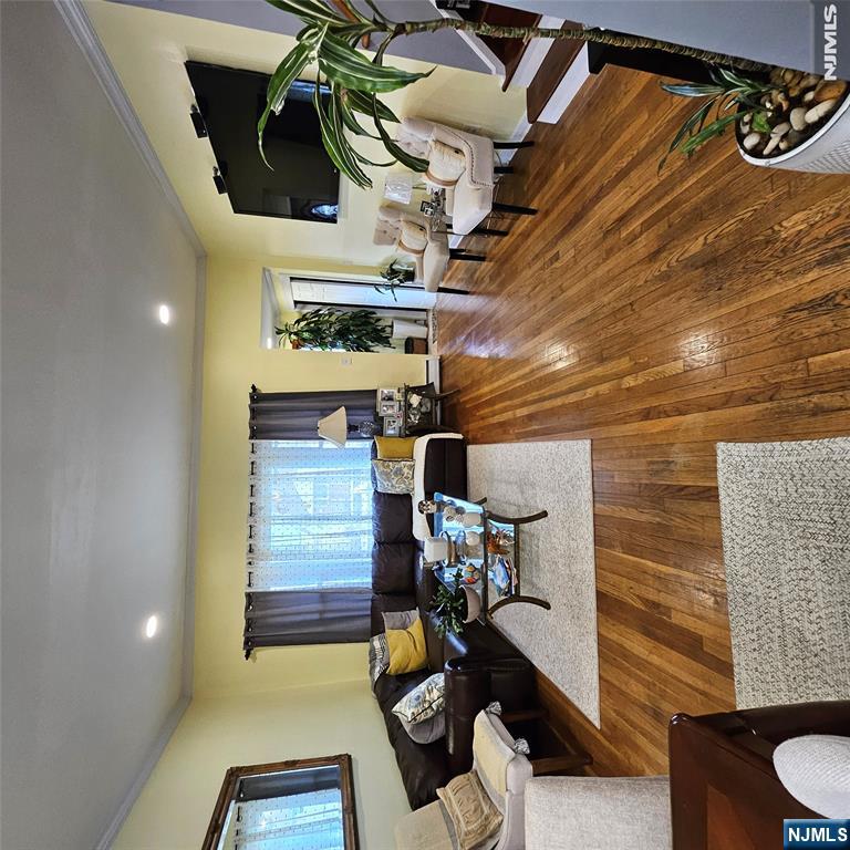 Living room with a dark sectional, polished hardwood floors, and a wall-mounted television.