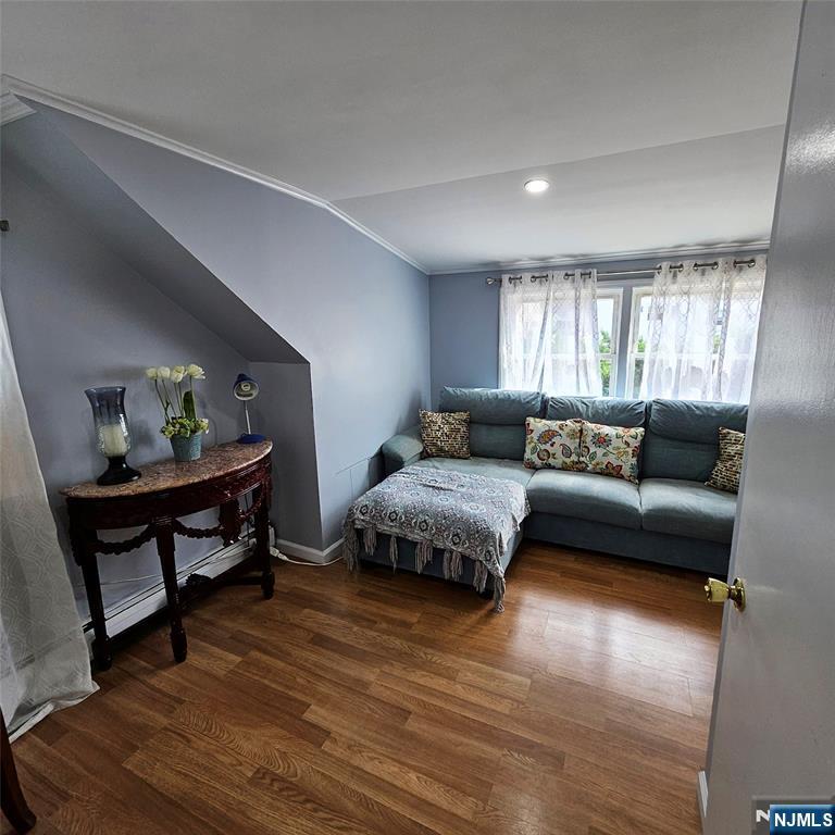 Living room with a teal sectional beneath a curtained window and hardwood floors.