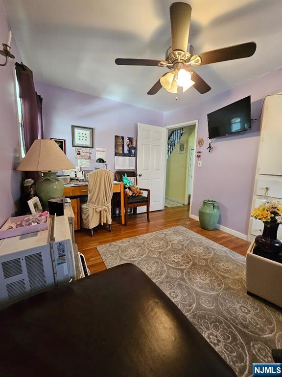 Furnished room with lavender walls, a desk, ceiling fan, and patterned area rug.