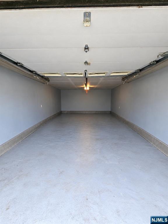 Empty garage with a concrete floor and raised overhead door.