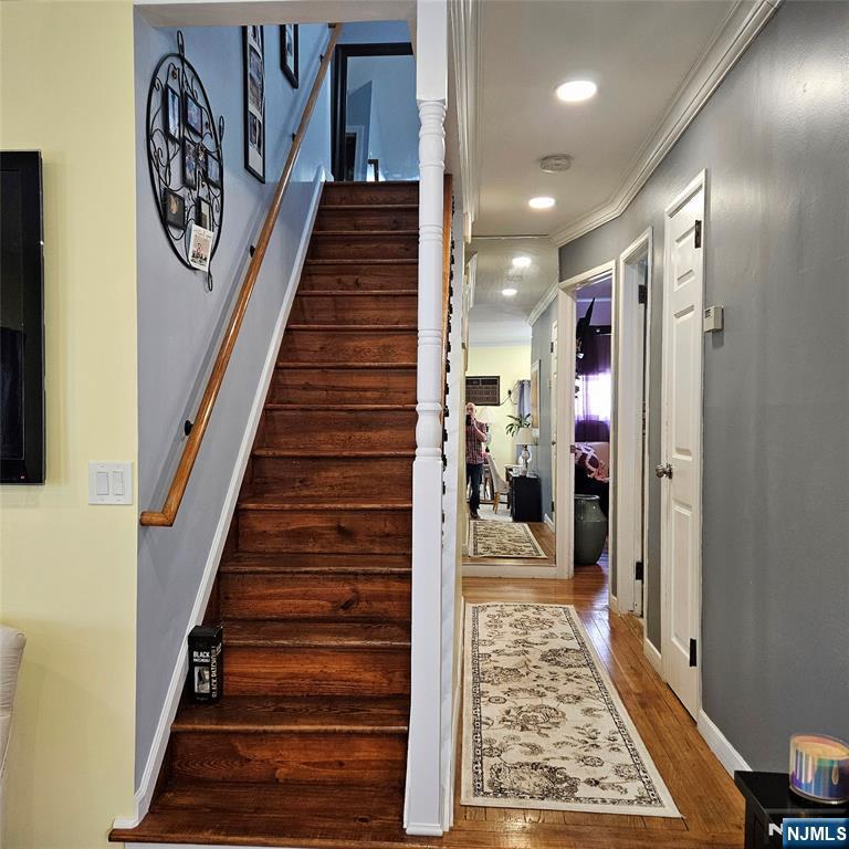Hallway with a dark wood staircase, hardwood floors, and patterned runner rugs.