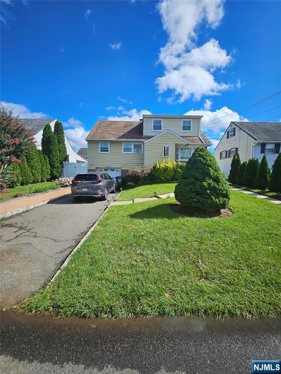 Two-story suburban house with a broad front lawn, paved driveway, and SUV parked outside.