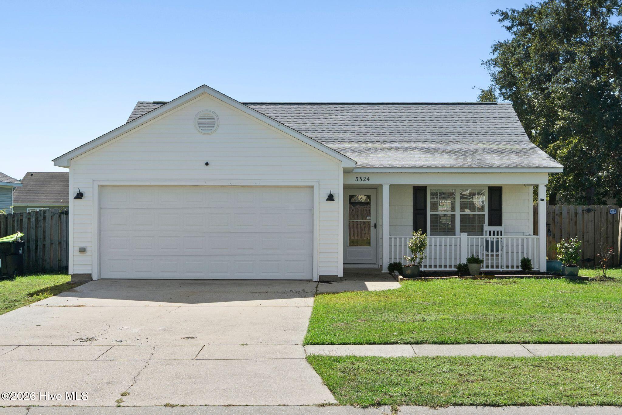 White single-story home with a two-car garage, covered porch, and front lawn.