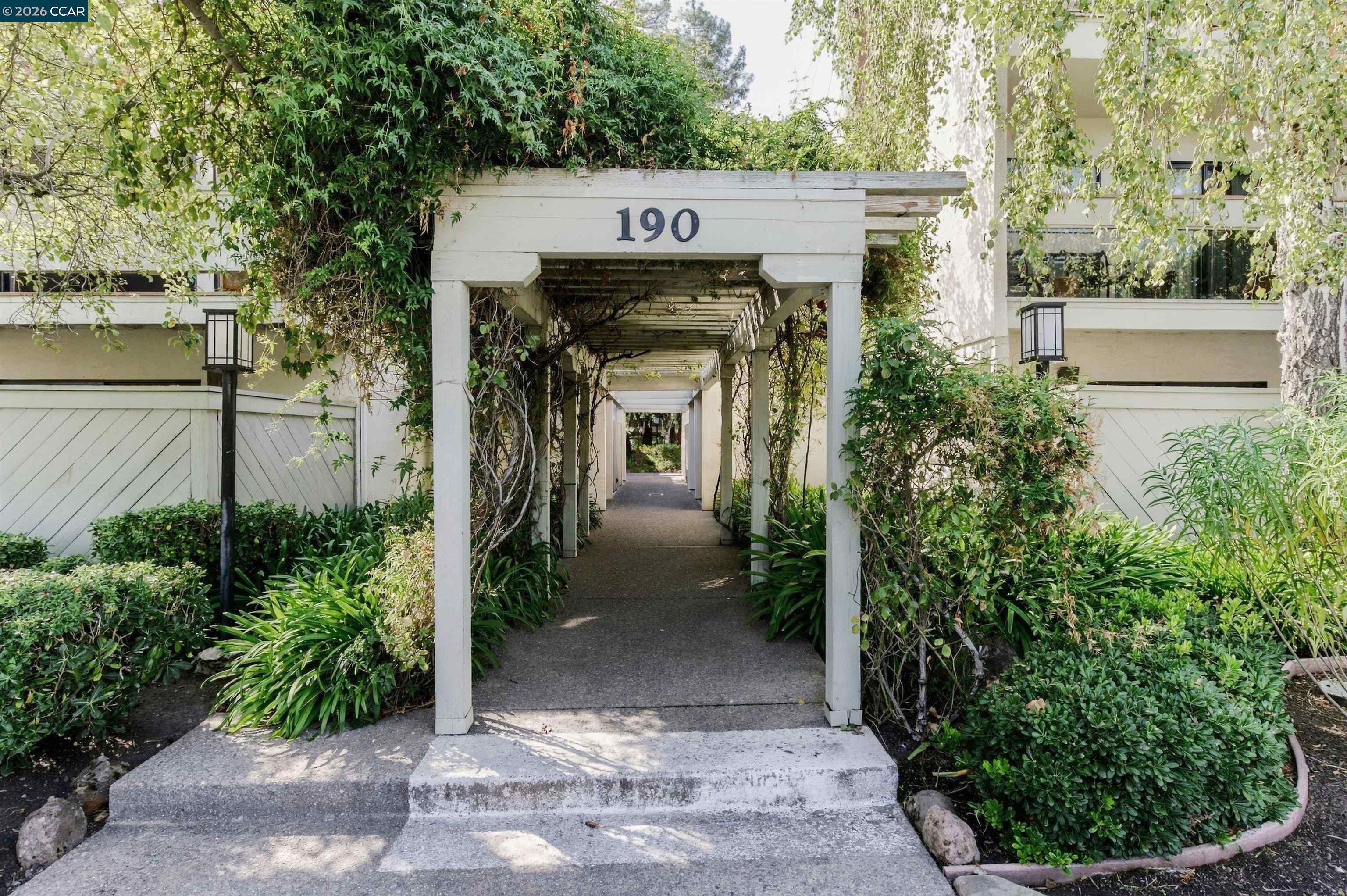 Residential entrance marked 190, with a white pergola walkway framed by lush landscaping.