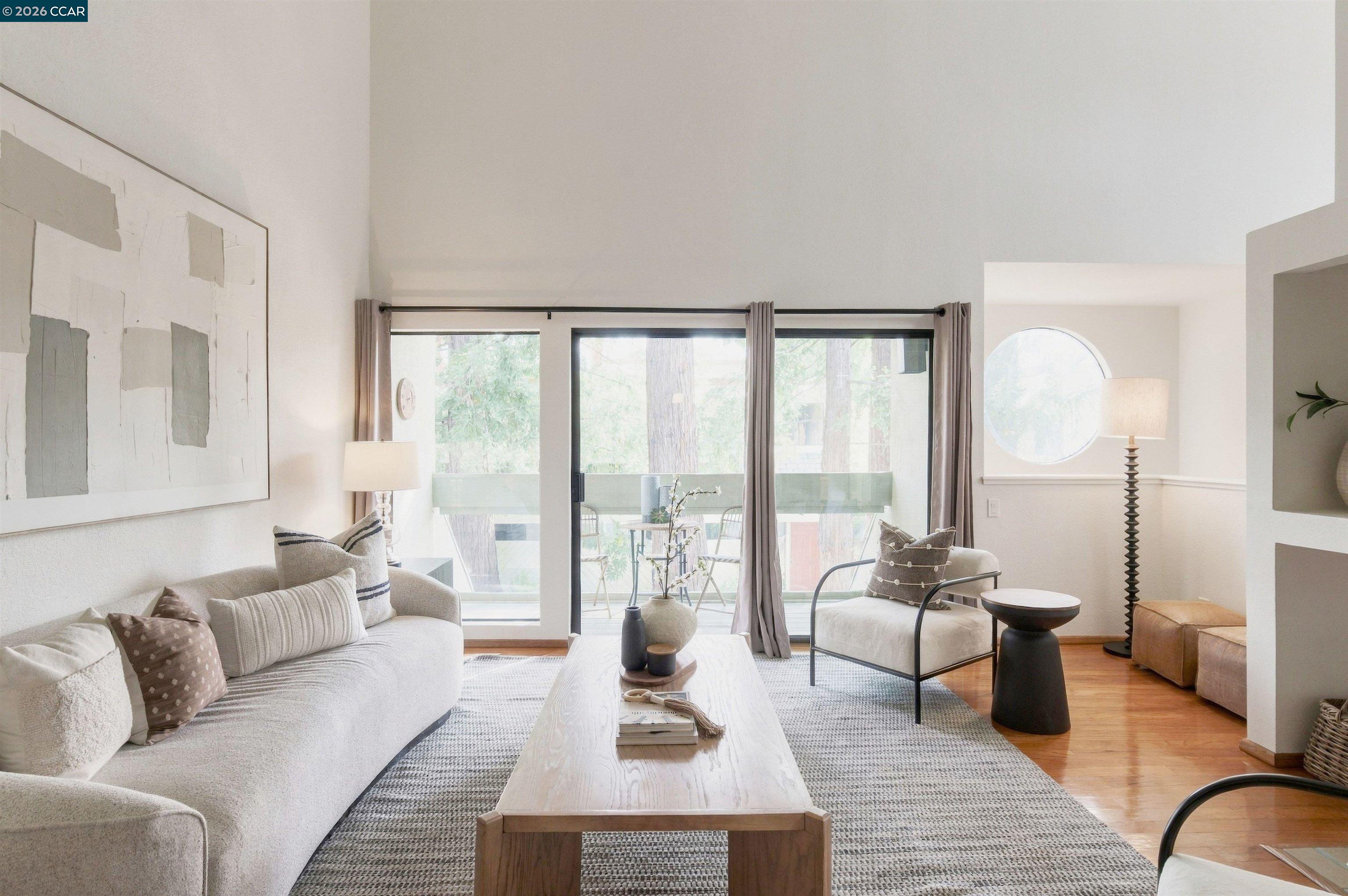 Staged living room with a light sofa, wood coffee table, sliding glass doors, and a round window.