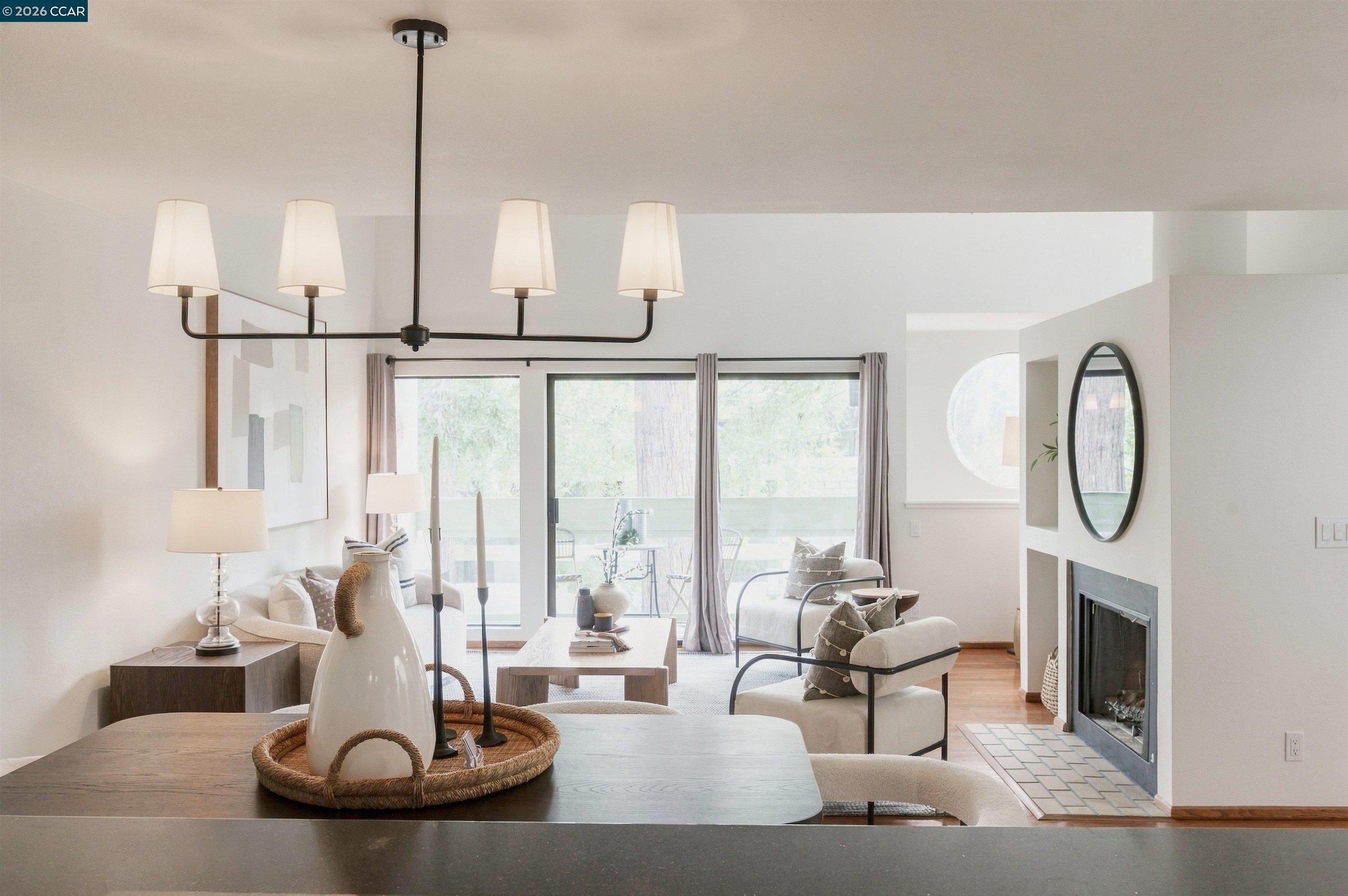 Staged living room with tiled fireplace, large windows, and sliding doors to a patio.