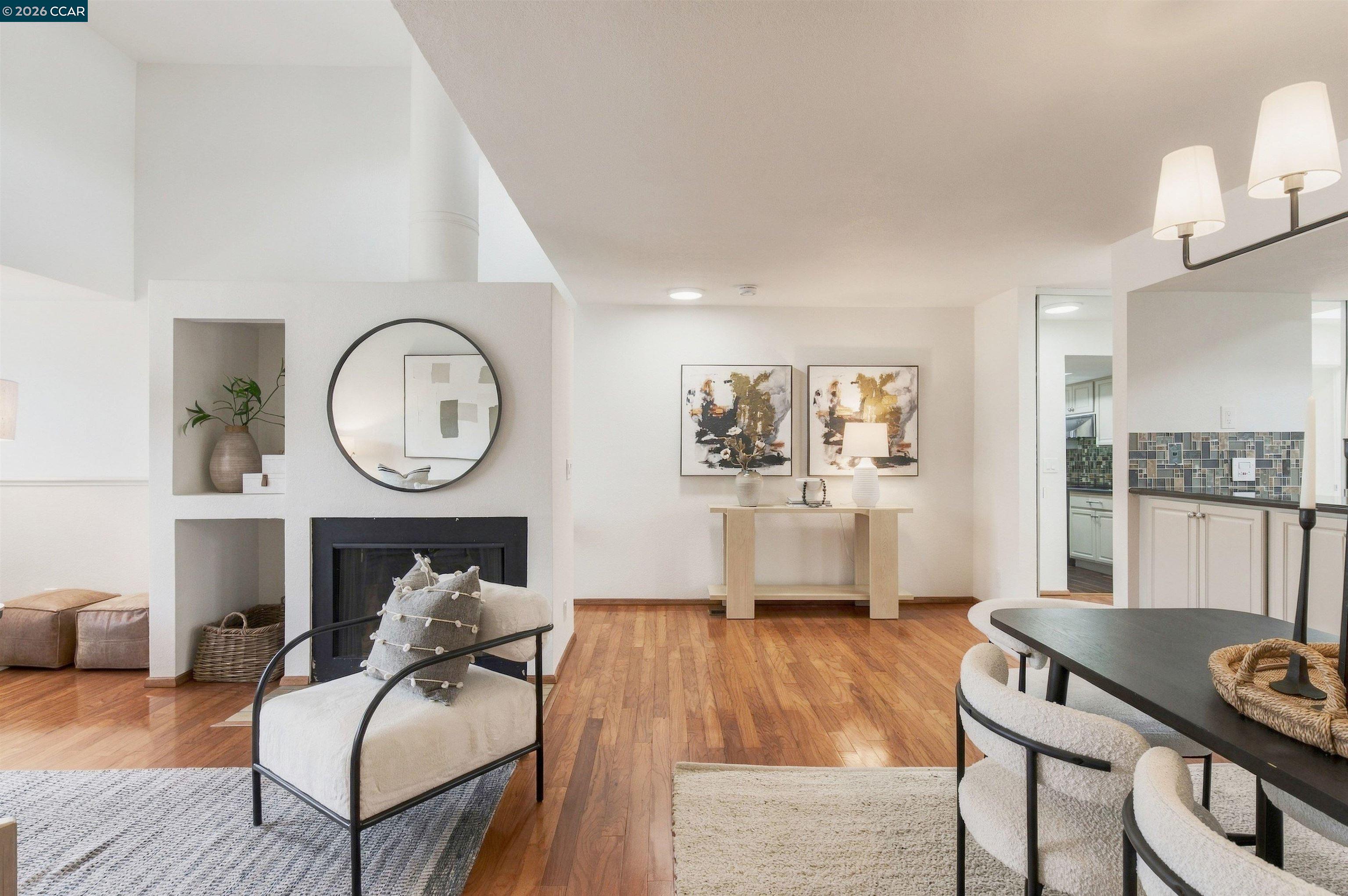 Open-plan living and dining room with hardwood floors, a built-in fireplace, and kitchen doorway.