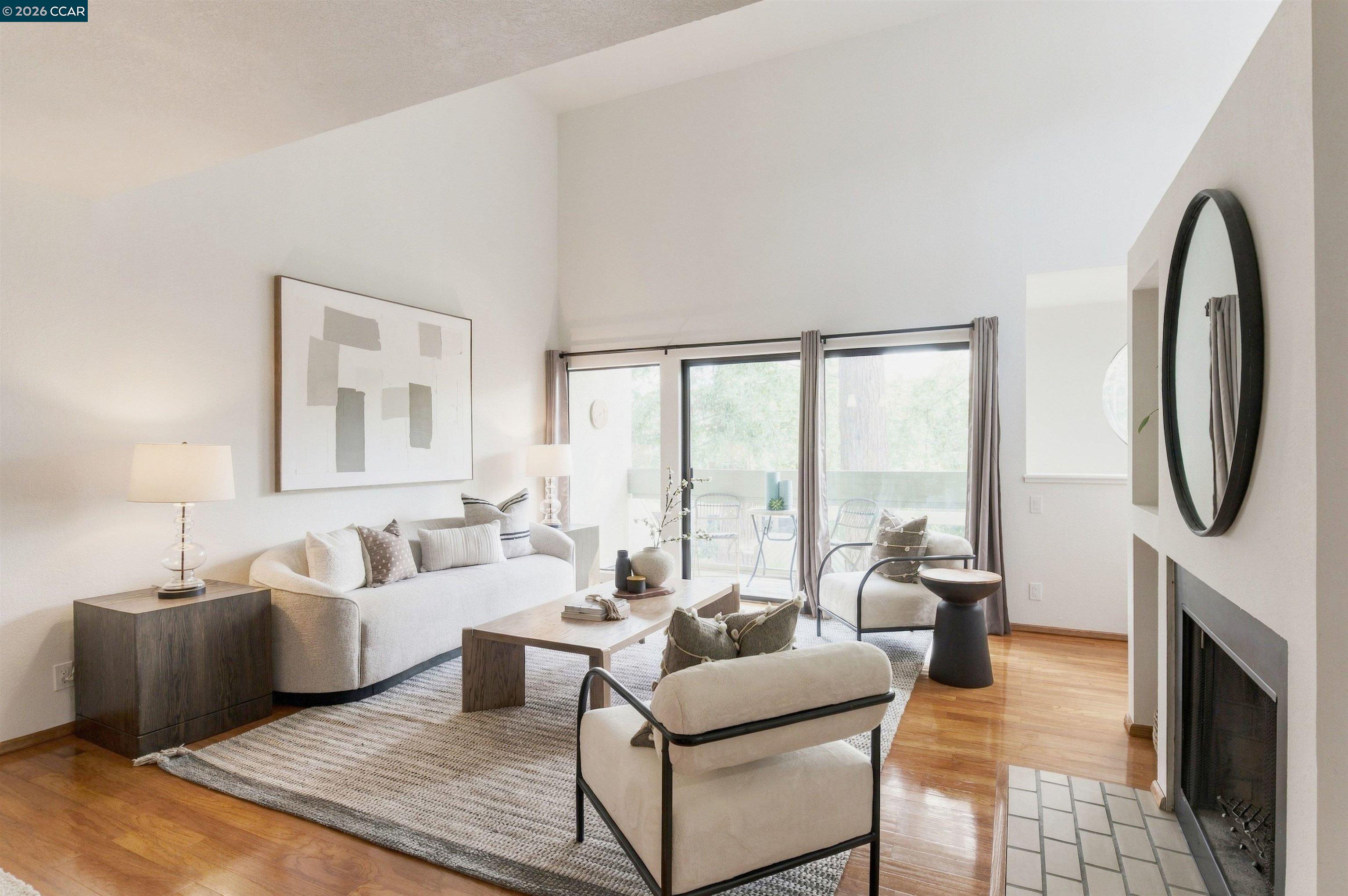 Staged living room with a fireplace, hardwood floors, and sliding doors to a balcony.