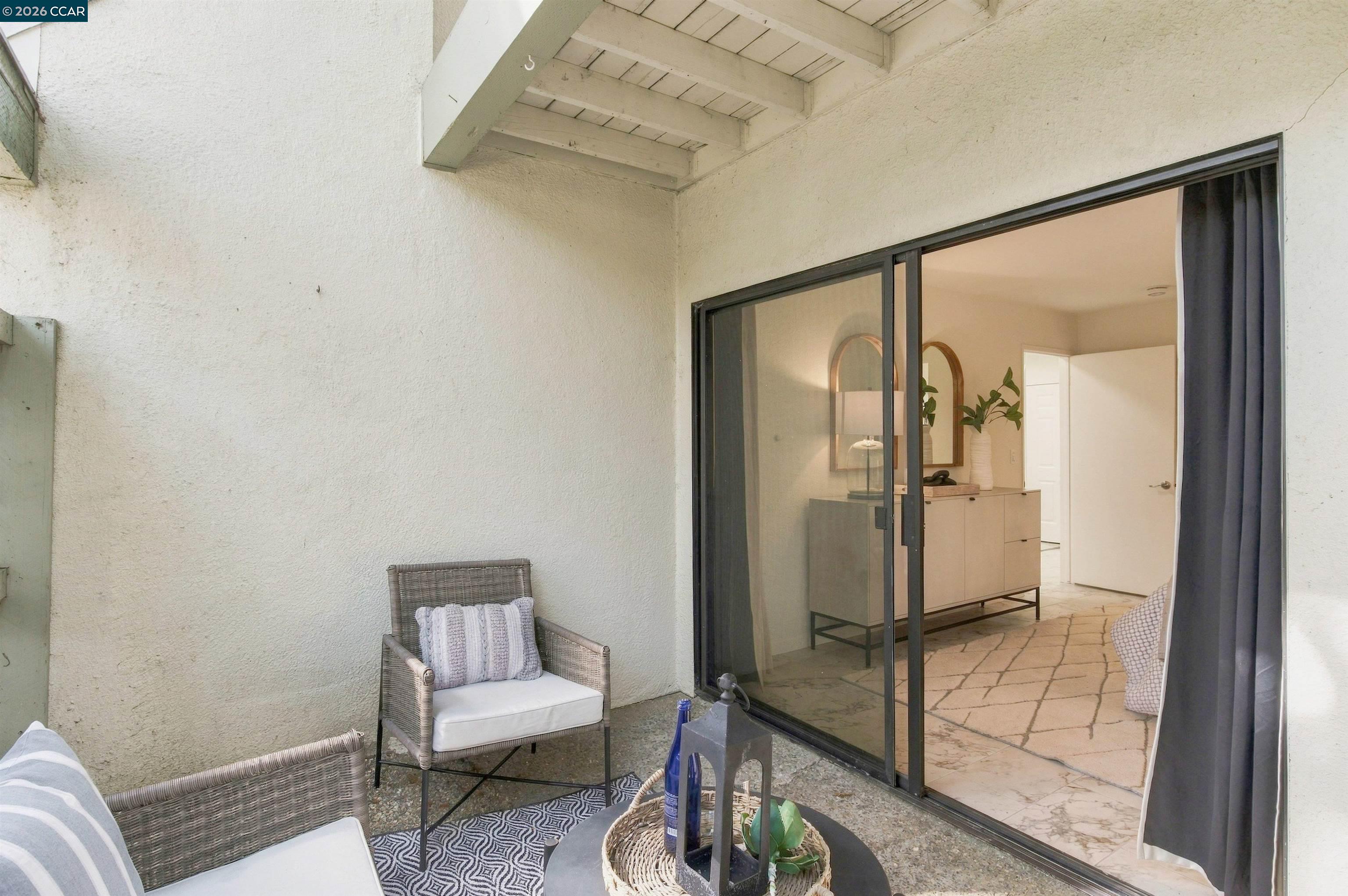 Covered patio with wicker chairs and a round table beside an open sliding glass door.