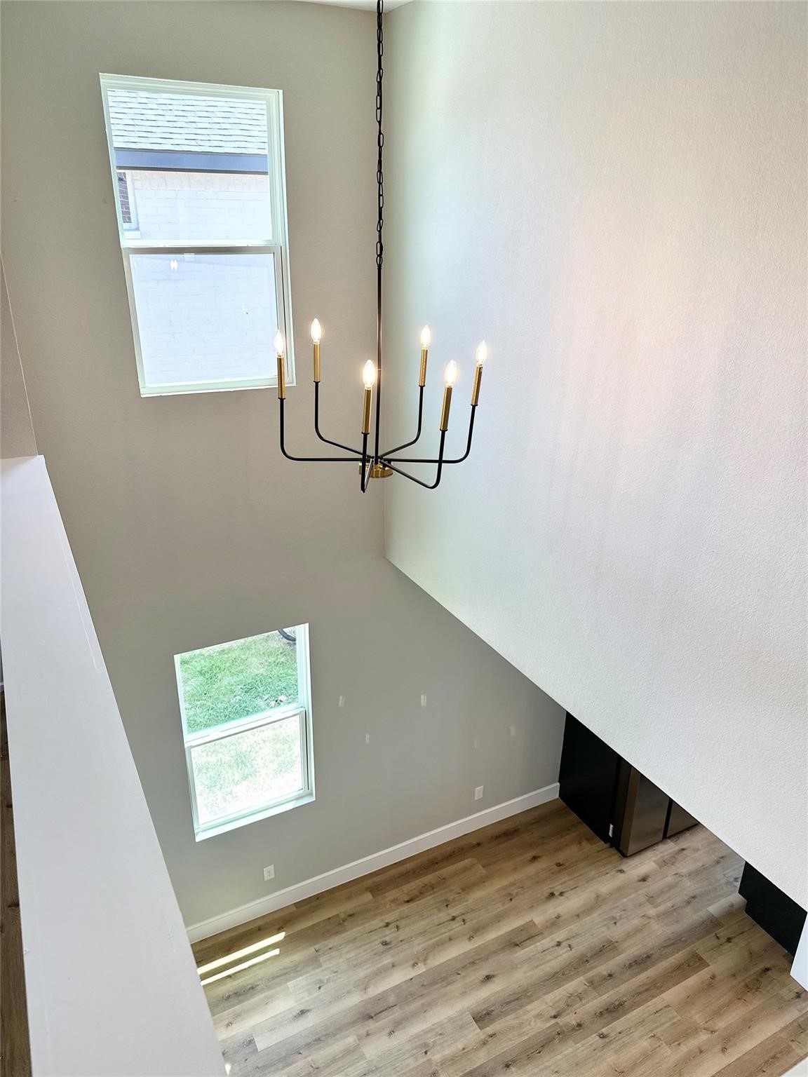 Two-story entry foyer with wood-look floors, tall windows, and a hanging chandelier.