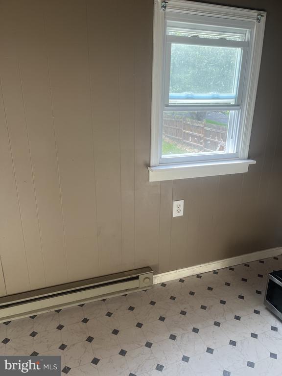 Empty room with a white-trimmed window, baseboard heater, and patterned floor.