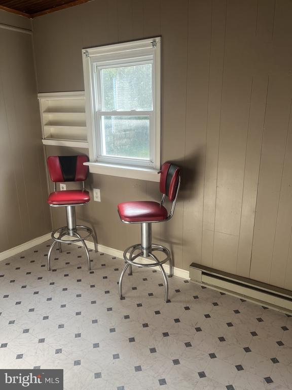 Room with two red swivel stools beneath a window and built-in wall shelves.